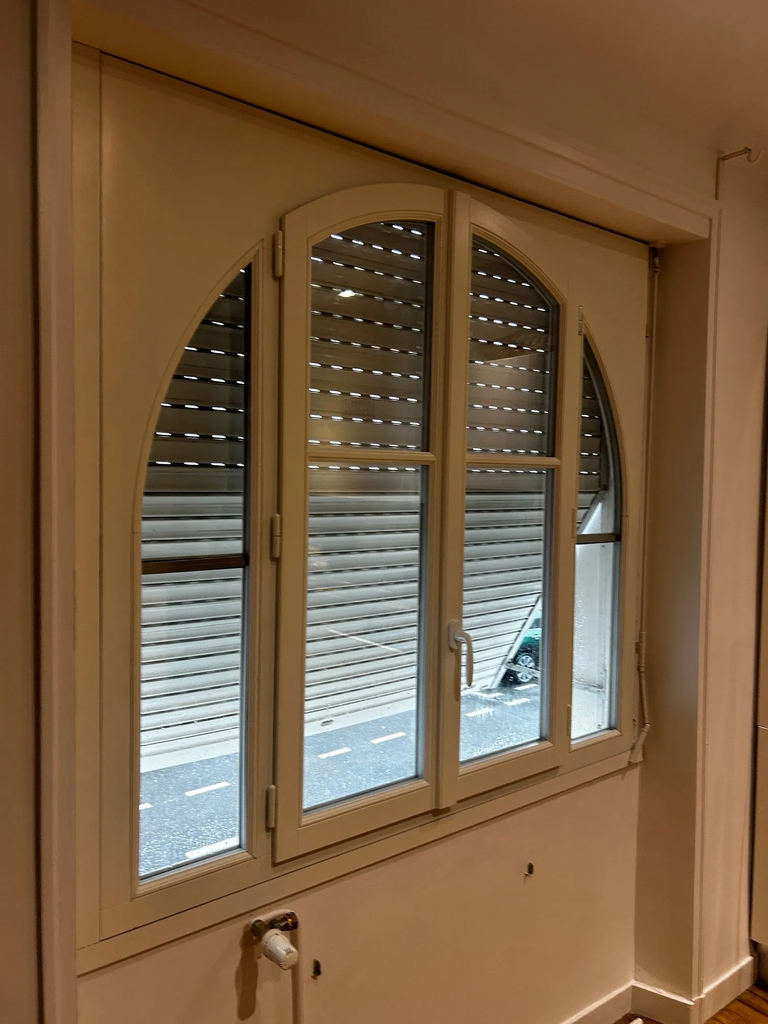 Volet roulant motorisé installé sur une fenêtre cintrée en intérieur, par Bonno Ouvertures.