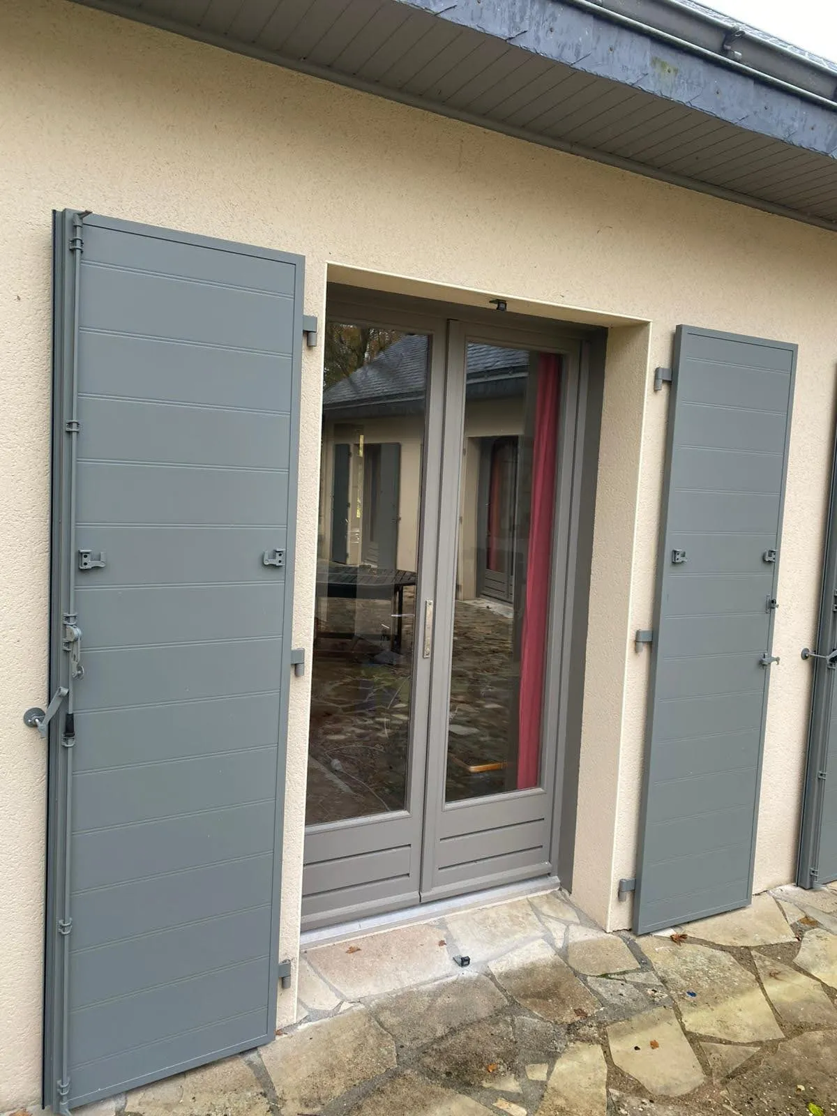 Volets battants en aluminium gris posés sur une porte-fenêtre, par Bonno Ouvertures en Loire-Atlantique.