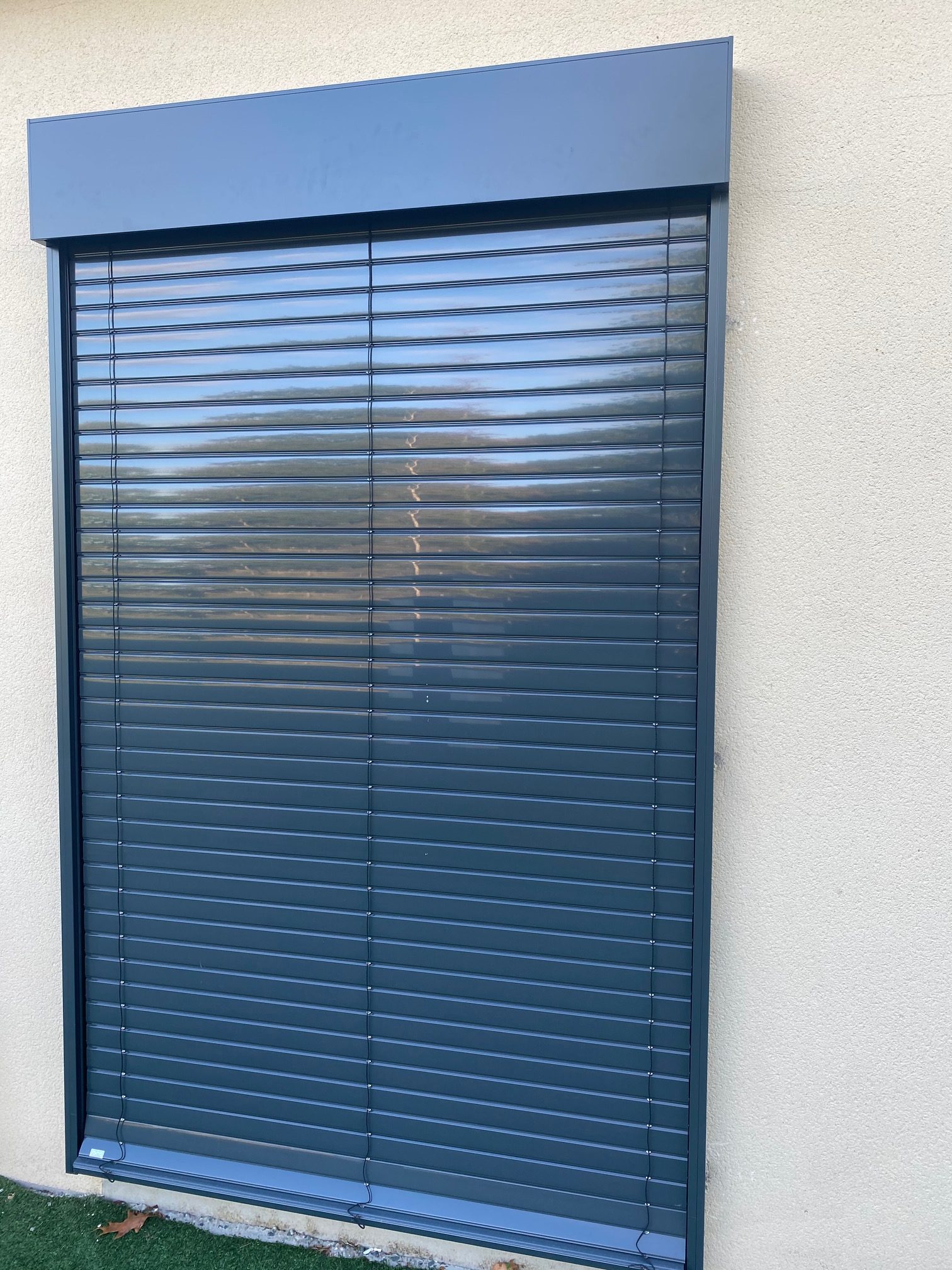 Brise-soleil orientable en aluminium gris foncé installé sur une baie vitrée, par Bonno Ouvertures.