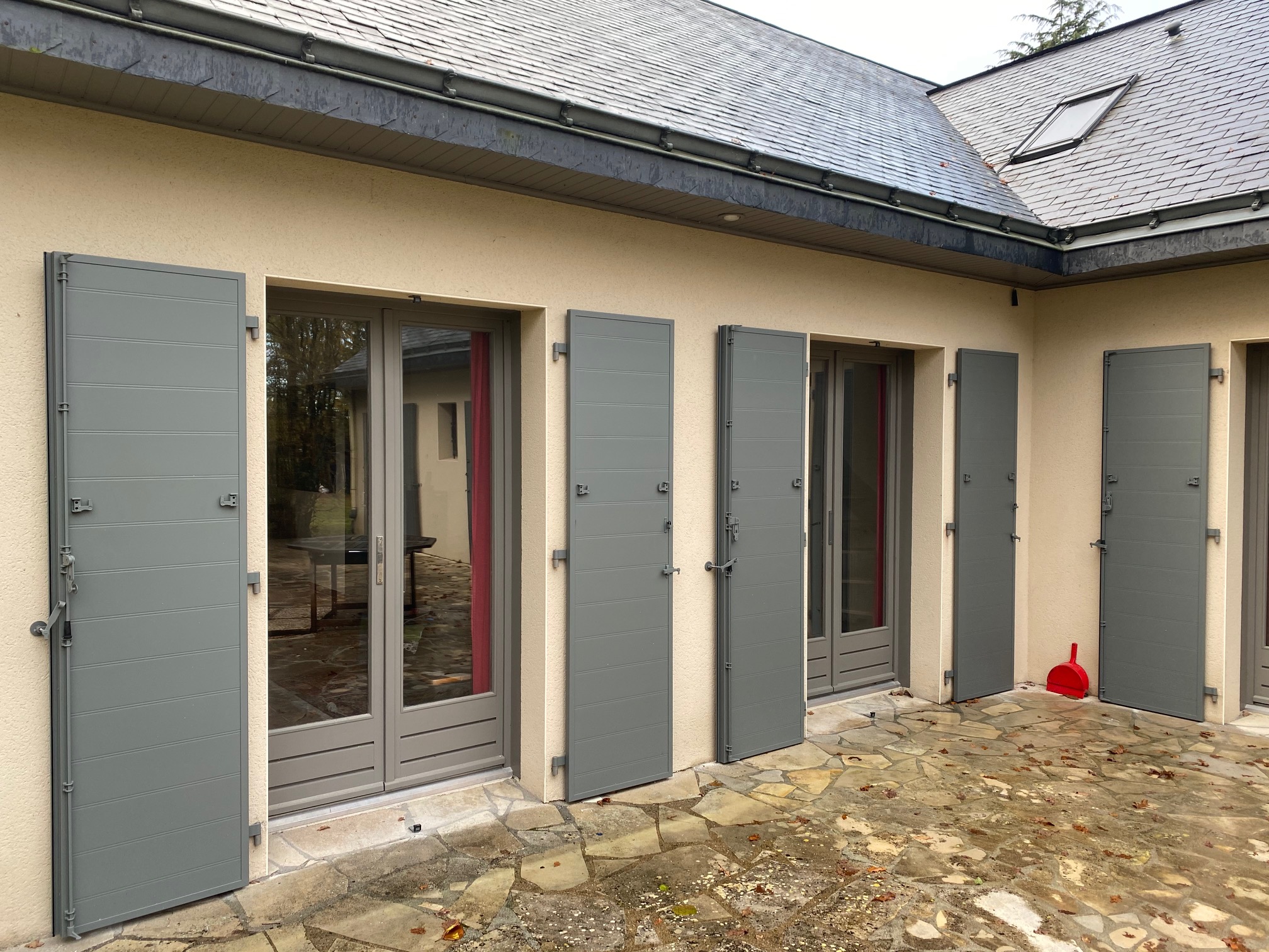 Fenêtre en bois peint gris clair avec volets battants assortis, posée en rénovation par Bonno Ouvertures.