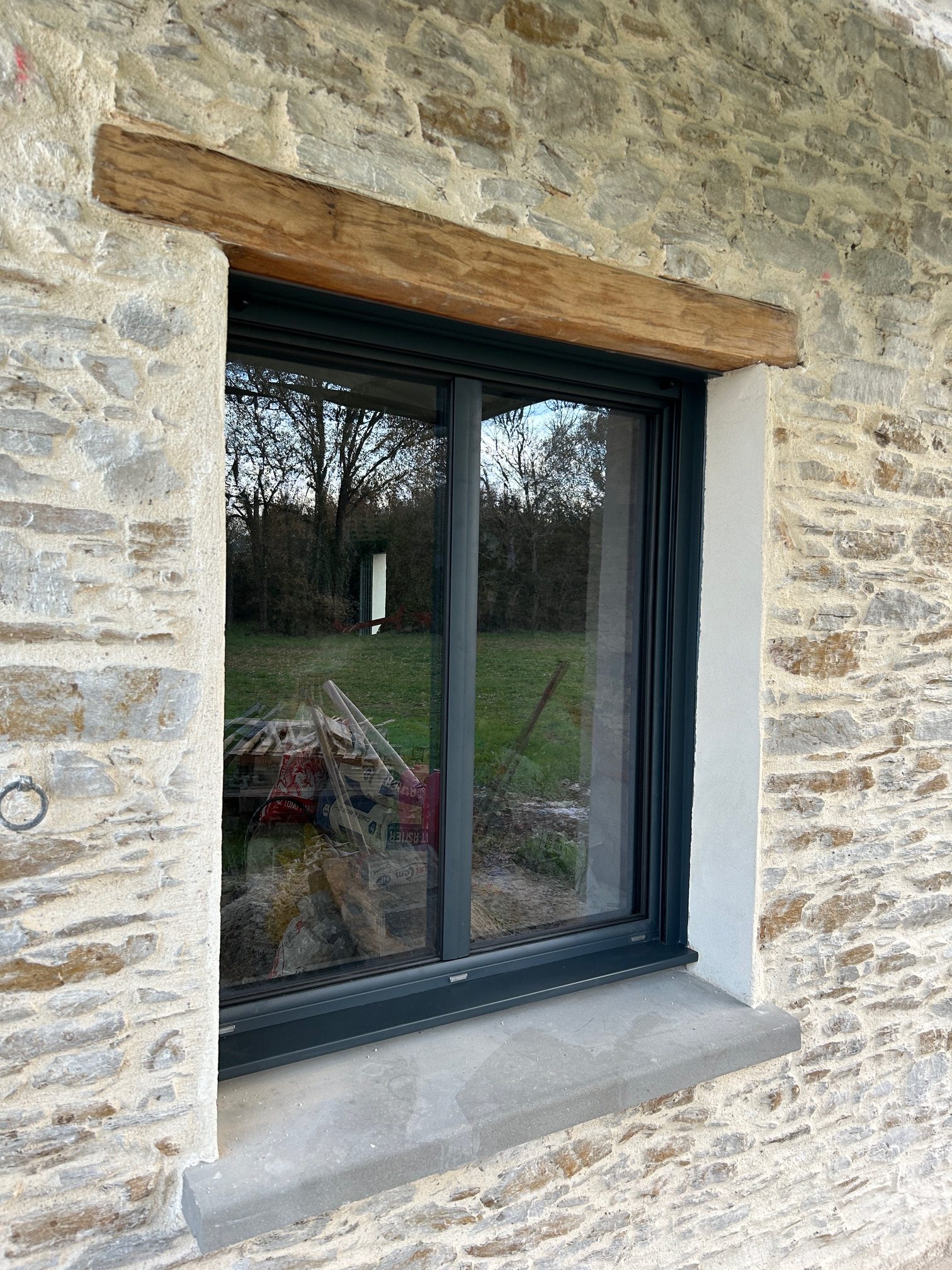 Fenêtre mixte bois/alu à ouvrant caché, posée sur une façade en pierre dans le cadre d’une rénovation, par Bonno Ouvertures.